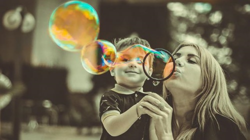 Zdjęcie mamy i dziecka dmuchających bańki mydlane